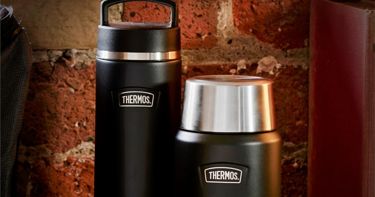 Two Thermos flasks standing against a brick wall in a warm interior